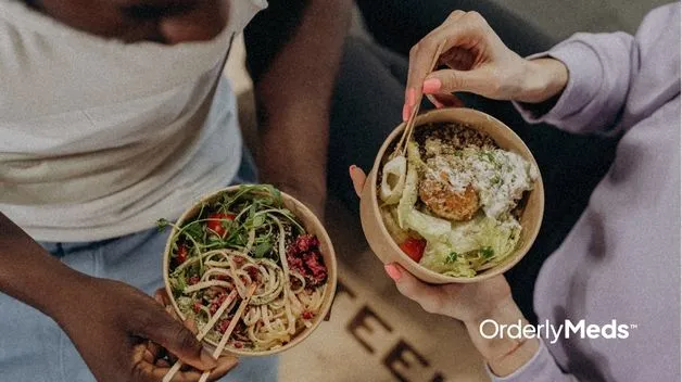 Closeup of two healthy bowls of food being help by two women on GLP-1 trying to follow the diet