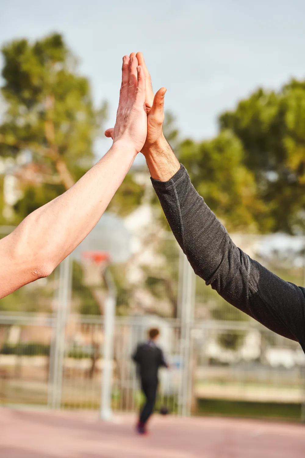 Two people high-fiving outdoors.